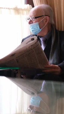 Maske takan yaşlı bir adam sessizce pencerenin kenarında gazete okur. Düşüncelerini ve hayatını yansıtır.