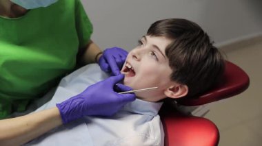 Genç bir çocuk diş bakımını rutin olarak yaptırıyor ve dişçi muayenehanesinde kapsamlı bir muayeneden geçiyor..