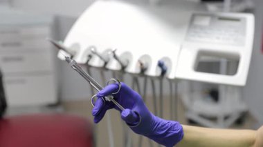 Bir diş hekimi, klinik bir ortamda önemli bir prosedüre hazırlanmak için özel bir enstrüman tutar..