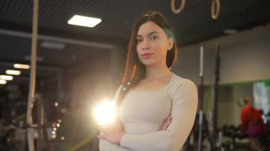 Kararlı bir kadın, modern bir spor salonunda, başarıya ulaşmak için tamamen hazır ve teçhizatlı duruyor.