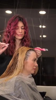 Saç boyama oturumu, şık bir salonda gösterilen profesyonel teknikleri vurguluyor.