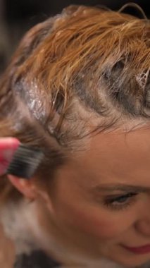 Bu yakın plan, desenli saç üzerindeki dikkatli boya uygulamasını vurgulayarak sanatsal saç boyama sürecini gösteriyor..