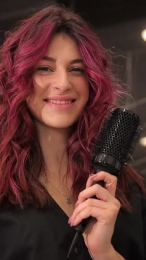 Canlı pembe saçlı neşeli bir genç kadın, kendine güvenen bir mikrofon tutuyor ve saf pozitiflik yayıyor.