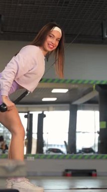 Spor salonunda dambılı olan atletik kadın antrenmanı. Dikey video.