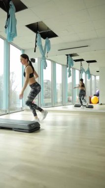 Parlak bir fitness stüdyosunda enerjik grup çalışması. Dikey video.