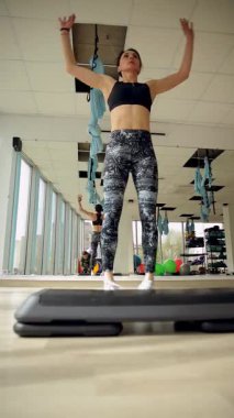 Formda bir kadın spor salonunda çeşitli egzersizler yapar, güç ve dayanıklılık gösterisi yapar. Dikey video.