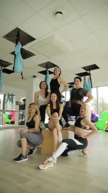Fitness meraklılarından oluşan dinamik bir ekip parlak bir spor salonunda güç ve birlik sergiliyor. Dikey video.