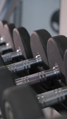 Modern bir spor salonunda dambılların yakın çekimi. Dikey video.