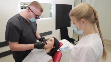 Modern bir diş kliniğinde, dişçi hastanın dişlerini dikkatle inceler.