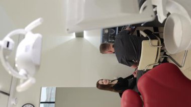 Bir hasta, modern bir diş muayenehanesinde bir dişçiyle çeşitli tedavi seçenekleri hakkında detaylı bir tartışmaya girer..