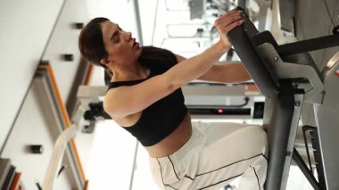 Kendini işine adamış bir kadın tüm dikkatini modern bir spor salonu ortamındaki rutinine verir.