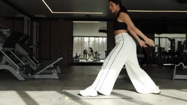 Bir kadın enerjik bir şekilde şık bir spor salonunda dinamik bir çalışma sergiliyor, sağlık ve zindeliği vurguluyor.