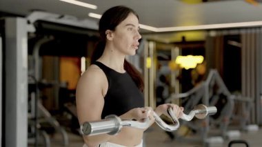 Kararlı bir kadın spor salonunda ağırlık çalışması yapıyor. Gücünü ve etkileyici spor yeteneklerini sergiliyor.