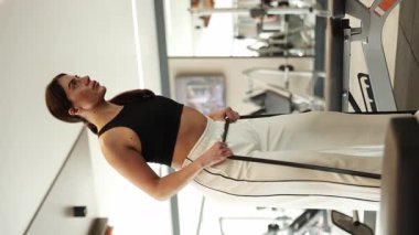 Çağdaş bir spor salonunda direnç bantları kullanan kendini adamış bir kadın güç ve kararlılık sergiliyor..