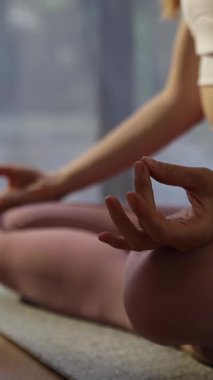 Yoga minderinde nilüfer pozisyonunda bilinçlilik alıştırması yapan bir kadının huzur verici bir atmosfer için doğal ışıkla yıkandığı huzurlu bir sahne. Dikey video