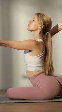 Spor kızı evde tek başına esniyor, vücut geliştirmeye ve kilo vermeye odaklanıyor. Dikey video.