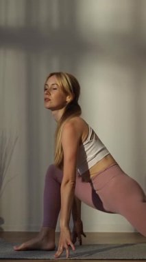 Yoga yapan kadın, güneşli bir stüdyoda egzersiz yapıyor, sağlıklı bir yaşam tarzını kucaklıyor ve dikkatli nefes alıyor. Dikey video.