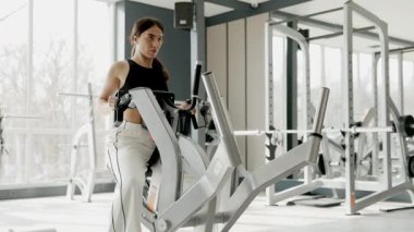Parlak, modern bir spor salonunda gelişmiş ekipmanlarla yoğun bir antrenman yapan bir fitness meraklısı.
