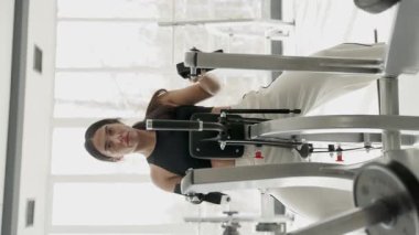 Bir kadın kürek çekme makinesinde çalışıyor. Formunu ve kararlılığını gösteriyor..