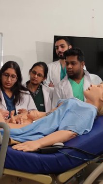 Bir grup Hintli öğrenci manken kullanarak ebelik eğitimi alıyor. Dikey video.