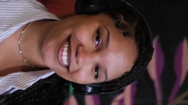 Yüzünde kulaklıkla gülümseyen Afrikalı Amerikalı kadın yaratıcılığa ilham veren parlak çalışma alanının tadını çıkarıyor..