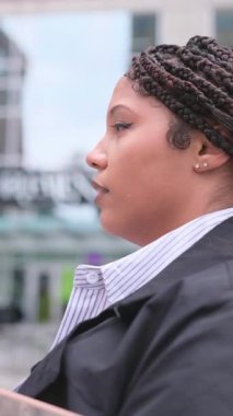 İş elbiseli Afrikalı Amerikalı bir kadın şehrin arka planında güvenle yürüyor..