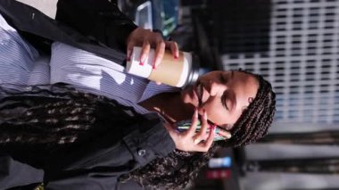 Kendinden emin Afrikalı Amerikalı bir kadın, genç bir profesyonel, telefonla konuşuyor, şehirde kahvenin tadını çıkarıyor..