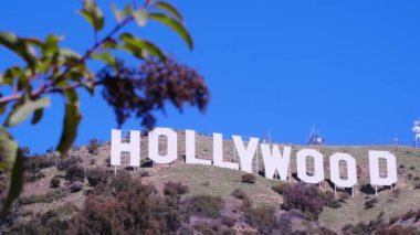Ünlü Hollywood tabelası açık mavi gökyüzüne karşı duruyor, eğlence endüstrisini simgeliyor..