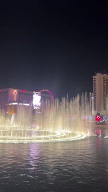 Göz kamaştırıcı bir çeşme gece gökyüzünü canlı renklerle aydınlatıyor ve Las Vegas ABD 'nin suyundan güzel bir şekilde yansıyor.