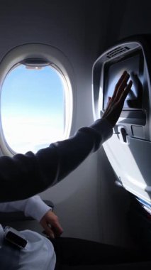 Bir yolcu yolcu uçağındaki monitörde eğlenmekten zevk alır..