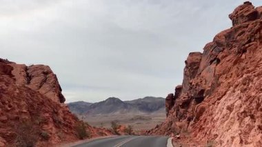 Sersemletici kırmızı kaya kanyonlarında, bulutlu bir gökyüzünün altında huzur içinde kıvrılan güzel bir yol..