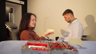 Bir cerrah kadına modern bir klinikte göğüs büyütme ve tedavi prosedürünü açıklar..