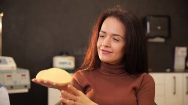 Yaklaşan estetik ameliyat sırasında göğüs implantı tutan kadın..