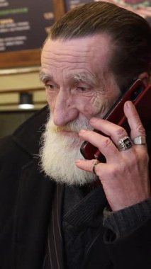 Seçkin ve bilge bakışlı yaşlı bir adam evde rahat otururken bir telefon görüşmesi yapıyor..