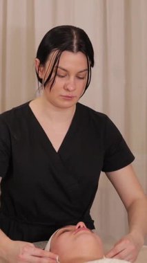 Huzurlu kaplıcada profesyonel yüz masajı. Sağlığı ve sükuneti destekleyen kadın ve erkekler için rahatlatıcı bir tedavi. Dikey vide