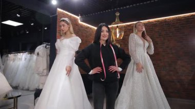 Şık bir gelinlik salonunda gelinlik seçmek. Bir satış danışmanı portresi ve gelinlik giymiş mankenler..