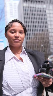 Koyu tenli Amerikalı bir kadının portresi gökdelenlerin arka planına karşı bir iş tarzında. Şehirdeki iş kadını.