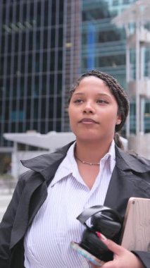 Koyu tenli Amerikalı bir kadının portresi gökdelenlerin arka planına karşı bir iş tarzında. Şehirdeki iş kadını.