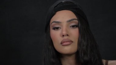 Kendine güvenen, uzun saçlı, şık şapkalı, cesur makyajlı, kendine güvenen bir kadının büyüleyici portresi.