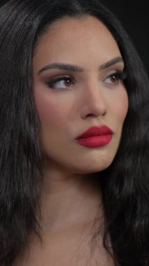 Zarif, çarpıcı makyaj sanatını ve uzun dalgalı saçlarını sergileyen bir kadının büyüleyici yakın plan fotoğrafı.