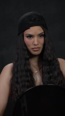 Şık şapkalı şık bir modelin büyüleyici bir portresi, güzel dalgalı saçları ve kendine güvenen bir ifadesi var.