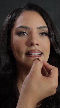 Ayrıntılı bir yakın çekim, zarif ve profesyonel bir dudak makyajı uygulamasından geçen bir modeli yakalıyor.