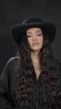 Şık bir siyah şapkayla tamamlanmış, uzun, dalgalı saçlı, kendine güvenen bir kadını gösteren inanılmaz şık bir portre.