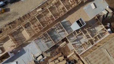 İnşaat alanının hava görüntüsü, ahşap çerçeve ve malzemelerin tamamlanma yolunda vurgulanması.