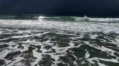 Karanlığın altında dramatik okyanus dalgaları kıyıya çarpıyor, kara kara düşünen bulutlar gerçekten yoğun bir atmosfer yaratıyor.