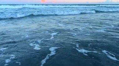 Okyanusun dingin güzelliği, nefes kesici bir gün batımının altında dingin bir atmosfer yaratır..