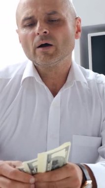 Modern ofis ortamında özenle para ve para sayan kararlı ve odaklanmış bir işadamı.