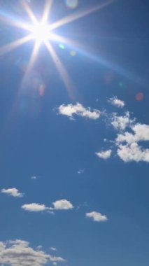 Bu çarpıcı görüntü berrak mavi gökyüzünde parlayan parlak bir güneşi ve dağınık kabarık bulutları gösteriyor.