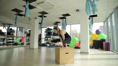 Yoga meraklısı biri modern bir beden eğitimi dersinde denge, güç ve dinamik bir ortamda vücut kontrolü üzerine çalışan bir kutu üzerinde amuda kalkma eğitimi alır..