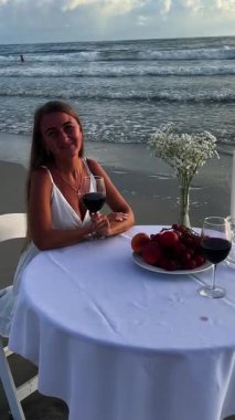 Sahilde nefis bir akşam yemeği kırmızı şarap ve taze meyveyle çarpıcı bir günbatımının arka planına karşı..